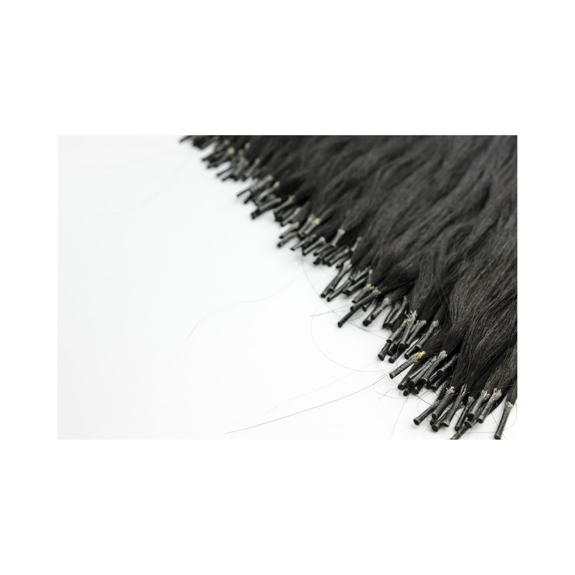 Close-up of black I-Tip Remy Extensions - Human Hair showing reusable tips for safe and secure hair application in professional styling.